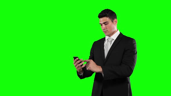 a Caucasian man in suit using a phone in a green background