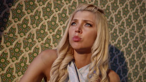 Portrait of a Blonde with Long Hair and a Passionate Face Against a Patterned Wall alt