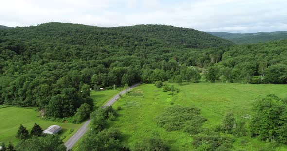 A car rolls down a road toward the overlapping mountains in the landscape of the Catskill Mountains alt