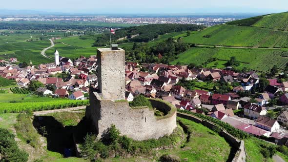 Cinematic aerial shot of old ruined castle overlooking Alsatian village