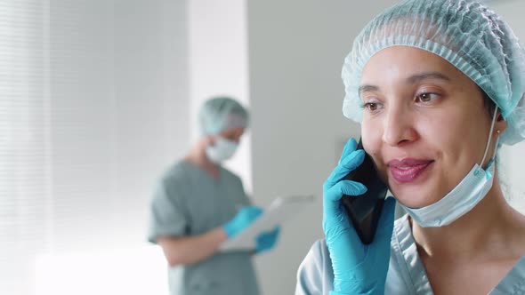 Cheerful Female Doctor in Protective Uniform Talking on Mobile Phone alt