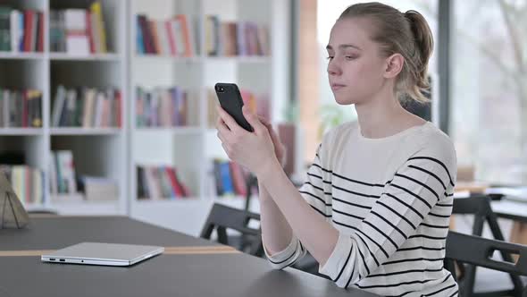 Smartphone Use By Serious Young Woman in Library alt