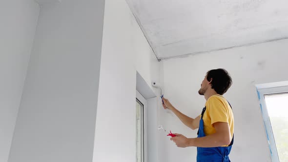 A Man Professional Construction Worker Paint the Wall Using a Roller Painter alt