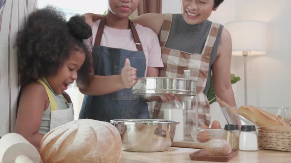 Happy African American family preparing flour to make bread in kitchen at home.