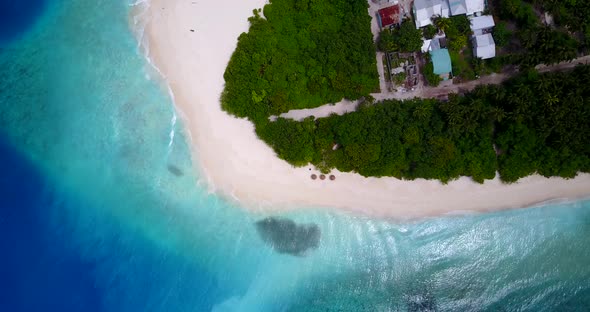 Wide angle above island view of a white sand paradise beach and blue sea background in vibrant 4K alt