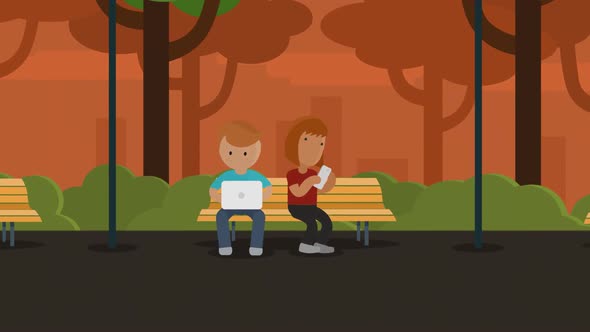 Young people sitting on a bench in the park using laptop and smartphone.