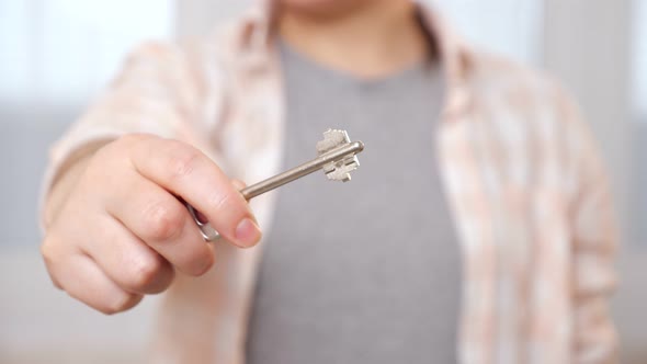 Young Woman Does Opening Door Gesture Holding Key in Room alt