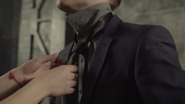 Female Hands Adjusting Black Tie of Man in Suit alt