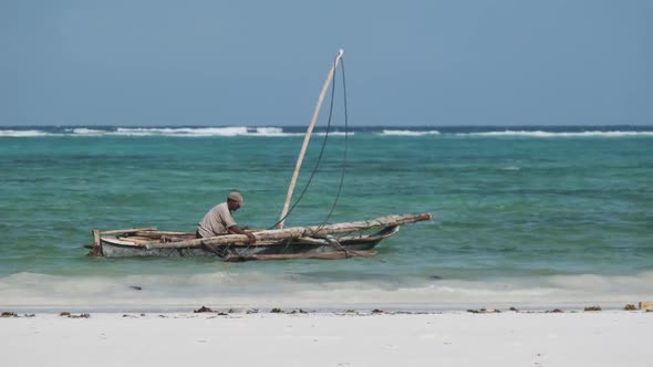 African Fisherman on an Old Dry Wooden Boat Sail in Ocean at High Tide Zanzibar alt
