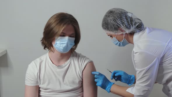 Medical Nurse is Making a Vaccine Injection to a Male Patient Indoor