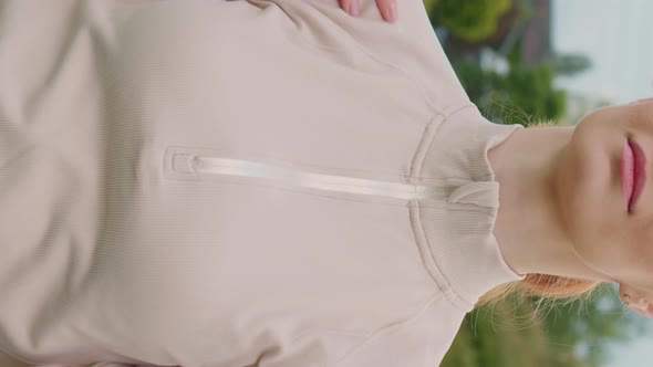 Vertical Screen Woman doing warm up exercise rotating shoulders in the park. alt