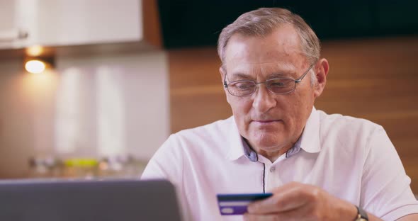 Concentrated Senior Man Making Online Payments of Bill Using Laptop Smiling Mature Woman Shopping alt