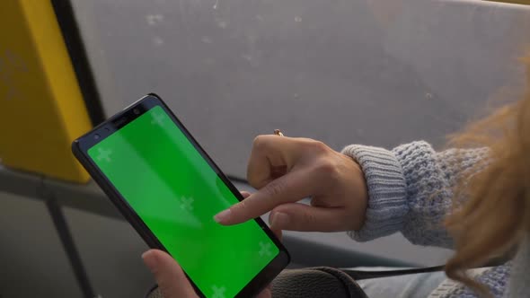 Woman's Hand Holding a Smartphone with a Green Screen in Tram. Chroma Key
