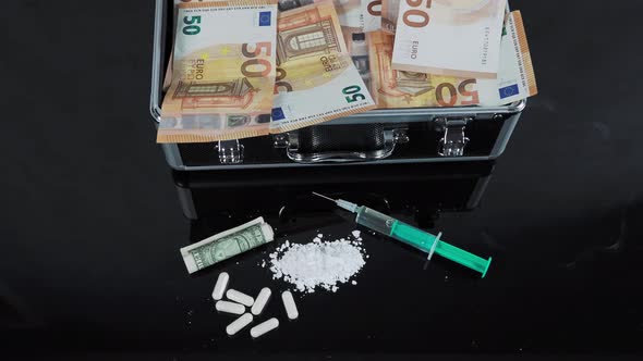 Money and drugs on a black glass table. Money, syringe and drugs. alt