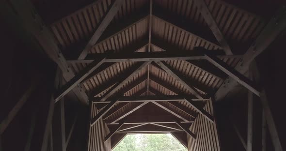 Looking up at the wooden truss ceiling within the dark, dramatic tunnel of the public Lowes covered alt