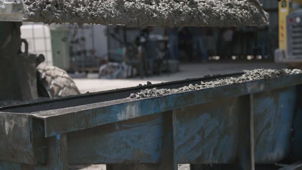 Workers pouring concrete into large steel molds on a construction site alt