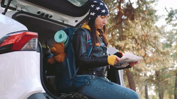 Pretty Woman Hiker Backpacker Traveler Camper with Her Phone Looks at a Map or Route on Forest Pine alt