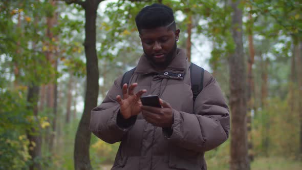 Black Male Traveler Browsing Phone During Hiking alt
