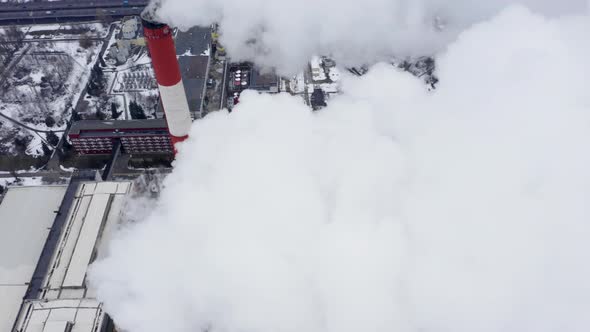 Aerial Observation of Snowy Industrial City with Two Huge Smoking Factory Pipes at the Foreground alt