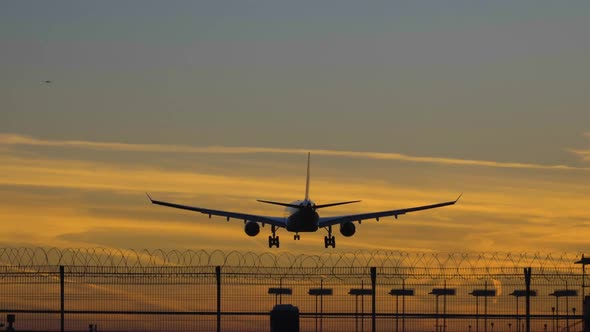 Silhouette of Airplane Landing at the Airport at Colorful Sunset alt