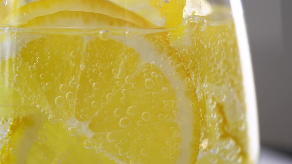 Close Up of Glass of Soda Water with Fresh Lemon Slices and Ice Rotates on Tray