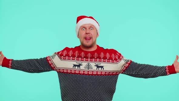 Crazy Man in Sweater Santa Christmas Hat Demonstrating Tongue Out Fooling Around Making Silly Faces alt