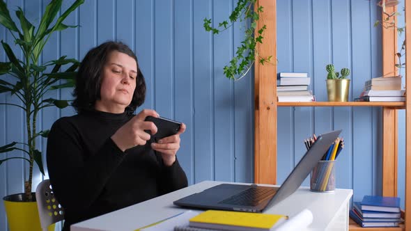 Middle Aged Woman Play Mobile Games or Uses Apps for Entertainment on Smartphone