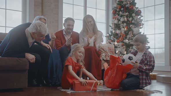 Kids Getting a Ball and a Teddy Bear As Gifts for Christmas Family Celebration alt
