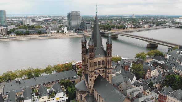 Aerial drone footage of Cologne Cathedral along the shore of the Rhine River in Germany. alt