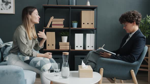 Side View of Cheerful Women Therapist and Client Talking and Smiling Indoors in Office alt