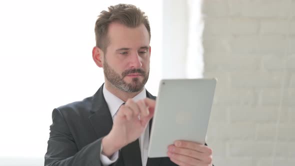 Attractive Young Businessman Using Tablet in Office alt