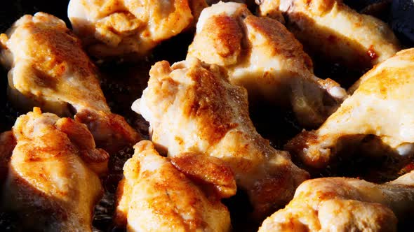 Chicken wings in boiling oil. Unbreaded chicken wings are fried in a pan in sunflower oil