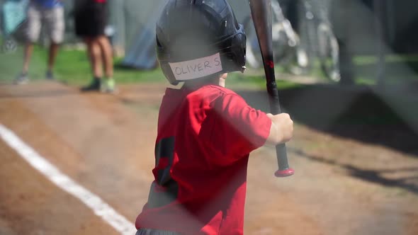 A boy is at bat while playing little league baseball. alt
