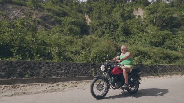 Handsome Man Traveling on Motorcycle at Summer Day. Senior Man Riding Motorbike on Tropical alt