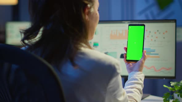 Freelancer Lookig at Mobile Phone with Green Screen Display alt