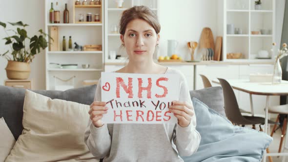 Woman Holding Poster with «NHS thank you heroes» Sign and Posing for Camera alt