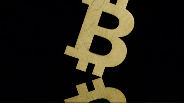 Golden bitcoin symbol falls on a black background