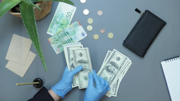 Unrecognizable woman hands in protective gloves with pile of money, counting US dollars bills alt