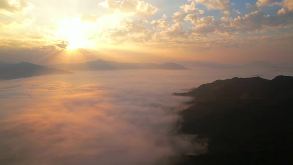 The rays of the sun shine through the clouds into the misty above the mountains in the morning alt