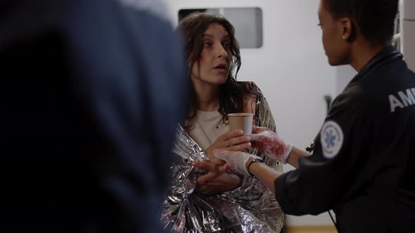 African Paramedic Giving Tea for Woman in Ambulance alt