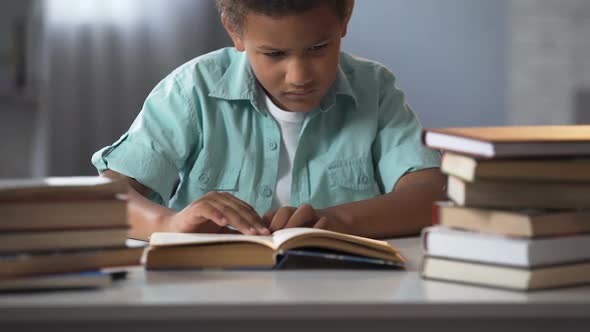 Male Child Tired of Doing Lot of Homework and Falling Asleep While Reading Book alt