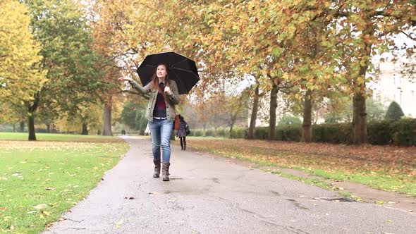 Happy woman walking at park on a rainy day in London