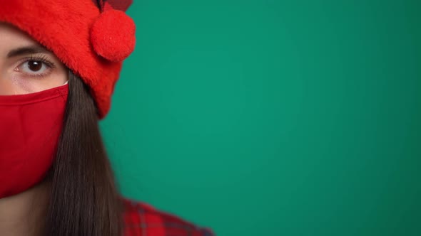 Portrait of Young Woman with Red Medical Face Mask and Santa Hat, Looking at Camera alt