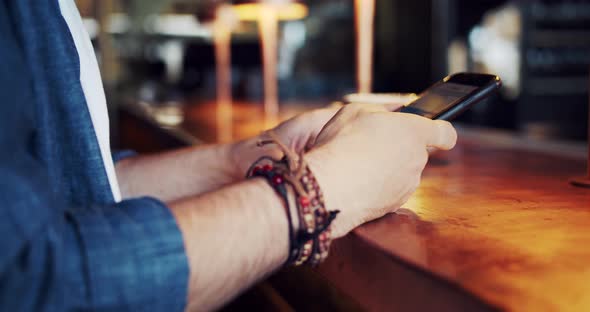 Male Browsing Social Net on Smartphone in Cafe