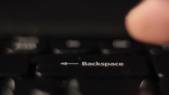 The Finger Presses the Backspace Button on the Keyboard. Close-up. alt