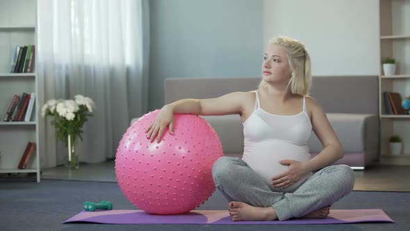 Pregnant Woman Thinking About Charms of Motherhood Tenderly Touching Her Tummy alt