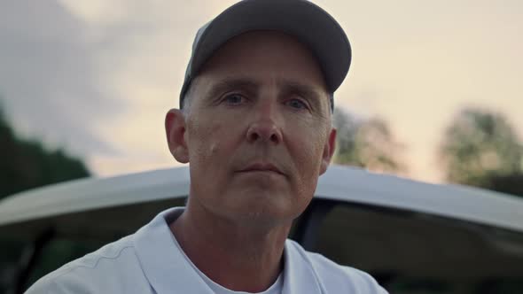 Pensive Senior Golfer Standing at Golf Cart alt