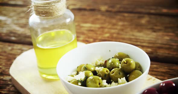 Red and green olives and olive oil on wooden board alt