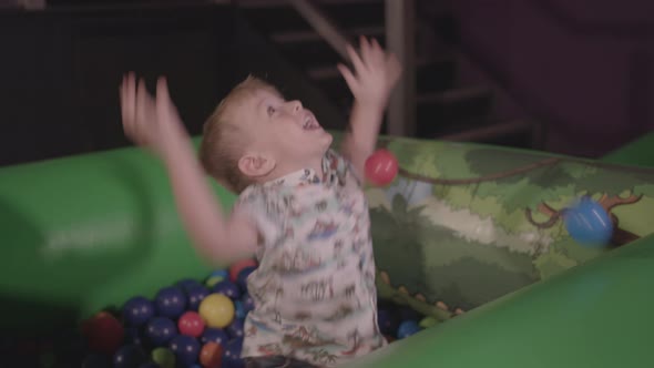Young Boy Playing in Ball Pit, Smiling and Throwing the Balls Around. - Ungraded alt