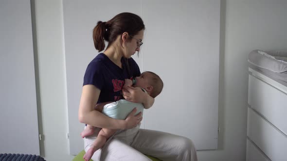 A Young Mother Rocks Her Baby on a Fitness Ball alt